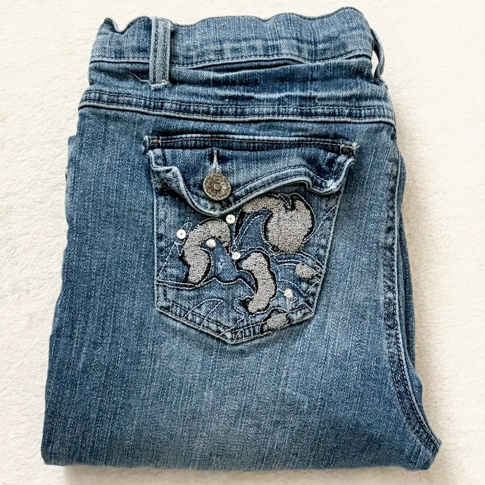 Low-rise, flared blue jeans with a silver snake design